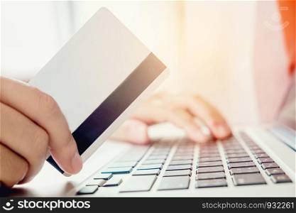 Woman shopping online using laptop with credit card enjoying in home