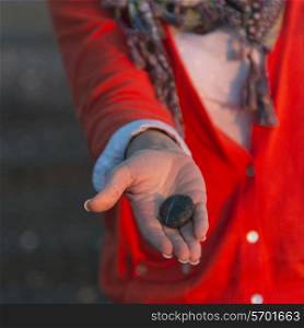 Woman showing a pebble on the beach, Trout River, Gros Morne National Park, Newfoundland and Labrador, Canada