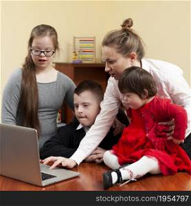 woman showing children with down syndrome something laptop
