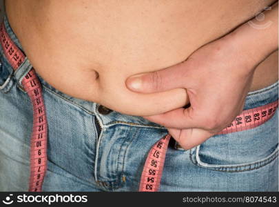 Woman showing fat belly. Pink tape measure