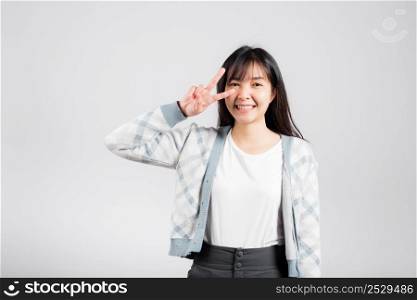Woman showing finger making v-sign victory symbol near eye looking to camera, Happy Asian beautiful young female mark peace gesture symbol, studio shot isolated on white background with copy space