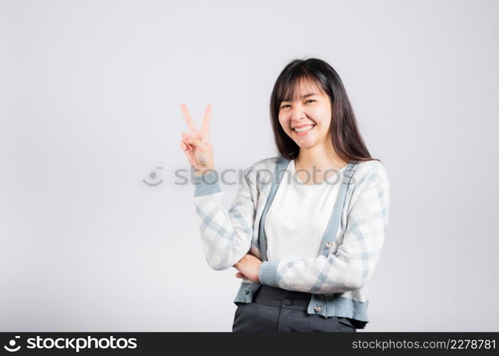 Woman showing finger making v-sign victory symbol side away looking to camera, Happy Asian beautiful young female mark peace gesture symbol, studio shot isolated on white background with copy space