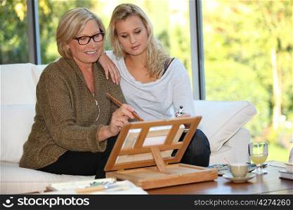Woman showing her granddaughter how to paint