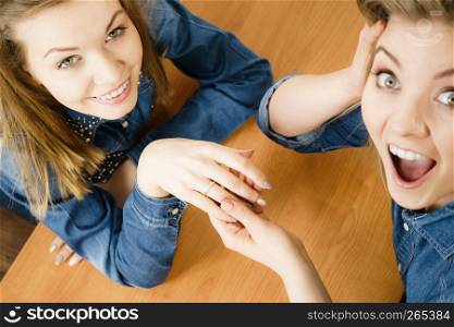 Woman showing her happy shocked female friend engagement ring sharing great news.. Woman showing her friend wedding ring