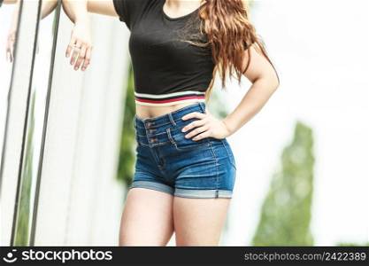 Woman showing her sexy curves. Hips and legs body part in short denim shorts.. Female buttocks in denim shorts