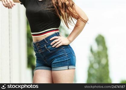 Woman showing her sexy curves. Hips and legs body part in short denim shorts.. Female buttocks in denim shorts