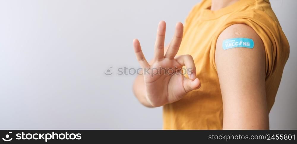 woman showing OK sign with bandage after receiving covid 19 vaccine. Vaccination, herd immunity, side effect, booster dose, vaccine passport and Coronavirus pandemic