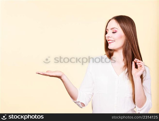 Woman showing presenting, long haired fashionable girl holding empty hand palm copy space for product. Beauty, fashion, advertisement concept. Studio shot on bright background. Woman holds empty hand copy space for product