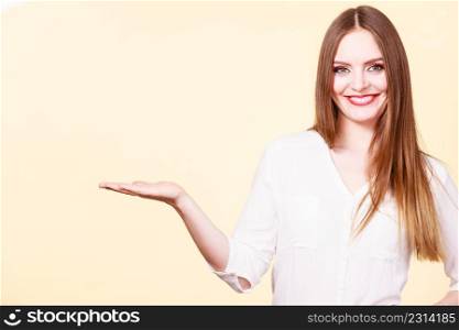 Woman showing presenting, long haired fashionable girl holding empty hand palm copy space for product. Beauty, fashion, advertisement concept. Studio shot on bright background. Woman holds empty hand copy space for product