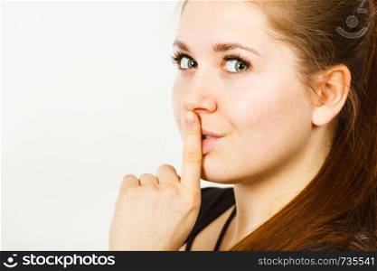 Woman showing silence shh gesture with finger close to mouth asking for being quiet. Woman showing silence gesture with finger