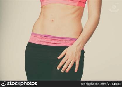 Woman showing some strong abs and flat slim naked belly close up. Part of thin female body. Fit fitness sport girl in sportswear. Woman showing some strong abs and flat belly