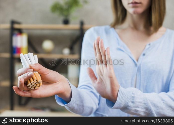 woman showing stop gesture holding bunch cigarettes hand