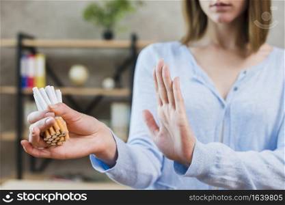 woman showing stop gesture holding bunch cigarettes hand