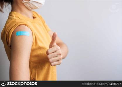 woman showing Thumb sign with bandage after receiving covid 19 vaccine. Vaccination, herd immunity, side effect, booster dose, vaccine passport and Coronavirus pandemic