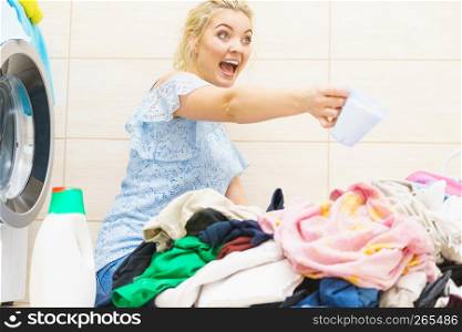 Woman showing washing powder detergent and measuring cup. Household duties, clothes laundry obejcts concept.. Woman showing washing powder