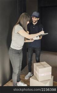 woman signing clipboard after parcel delivered by delivery man