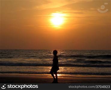 Woman silhouette at the sunset beach