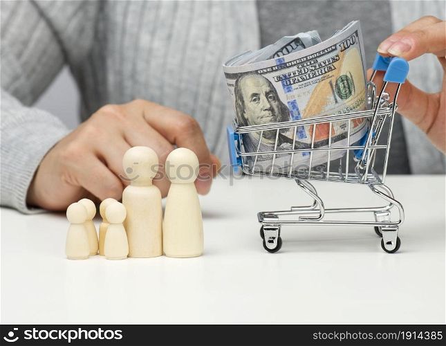 woman sits at a table and a miniature cart with US dollars. Concept of savings, sale, tax