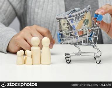 woman sits at a table and a miniature cart with US dollars. Concept of savings, sale, tax