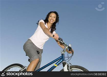 Woman sits on mountain bike against clear blue sky