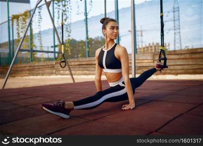 Woman sits on the splits on sports ground outdoors. Slim female person in sportswear, outside fitness training, fit workout. Woman sits on the splits on sports ground outdoors