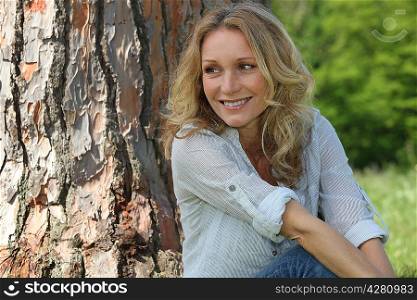 woman sitting against a tree