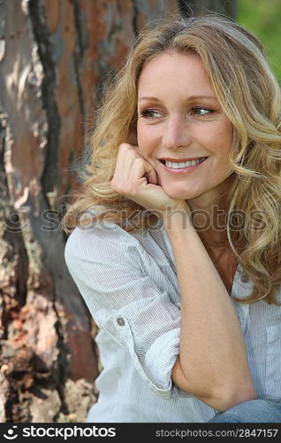 woman sitting against tree