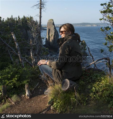 Woman sitting along Skerwink Trail, Port Rexton, Bonavista Peninsula, Newfoundland And Labrador, Canada