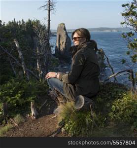 Woman sitting along Skerwink Trail, Port Rexton, Bonavista Peninsula, Newfoundland And Labrador, Canada