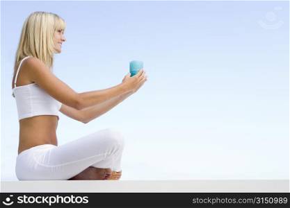 Woman sitting and meditating outdoors while holding a candle