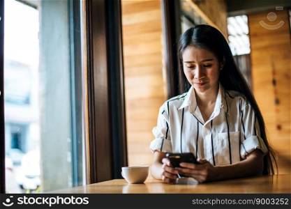 Woman Sitting and playing her smart phone at cafe