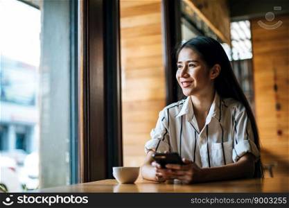 Woman Sitting and playing her smart phone at cafe