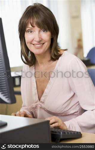 Woman sitting at a computer terminal typing (high key)
