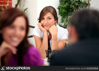 Woman sitting at a restaurant table with other diners in the foreground