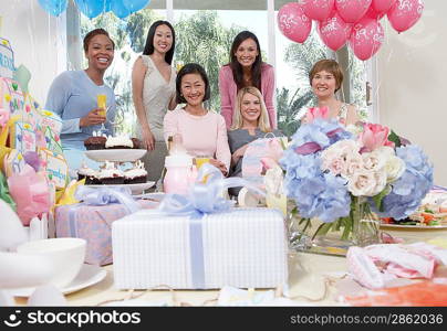 Woman sitting at baby shower behind table of gifts