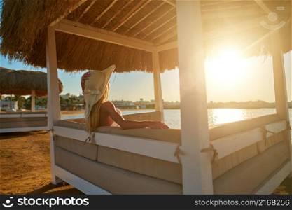 Woman sitting at Cabana with straw roof on a sandy beach on sunset.. Woman sitting at Cabana with straw roof on a sandy beach on sunset