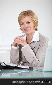 Woman sitting at her desk with laptop and open diary