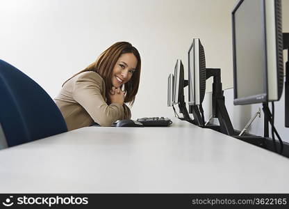 Woman sitting at row of computers, portrait