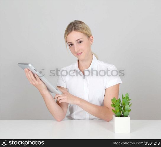 Woman sitting by green plant with electronic tablet