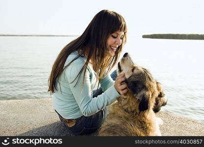 Woman sitting by lake with dog