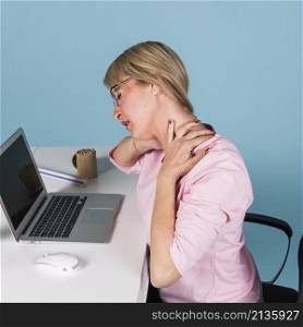 woman sitting chair suffering from neck pain while using laptop