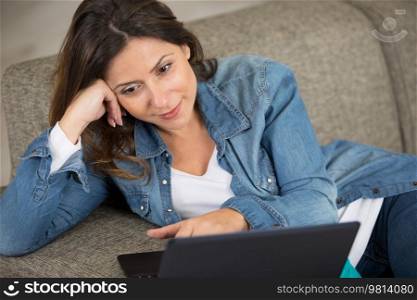 woman sitting comfortably on the sofa using a laptop