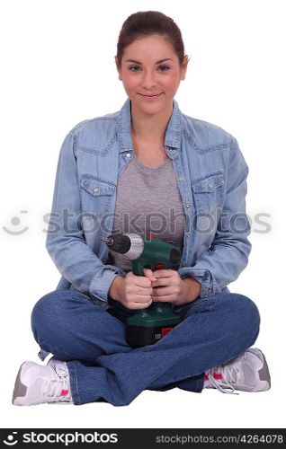Woman sitting cross-legged and holding an electric screwdriver