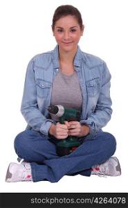 Woman sitting cross-legged and holding an electric screwdriver