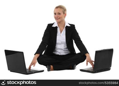 Woman sitting cross-legged in front of two computers