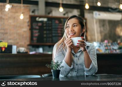 woman sitting happily drinking coffee in cafe shop