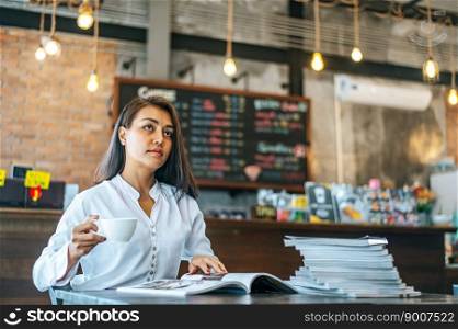 woman sitting happily drinking coffee in cafe shop and book