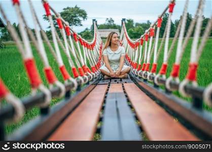 woman sitting happily on a wooden bridge