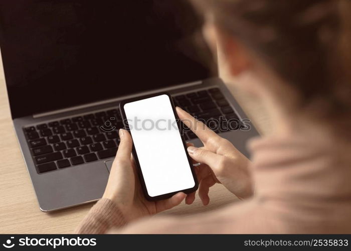 woman sitting her laptop using smartphone