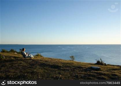 Woman sitting in a chair reading a book at seaside